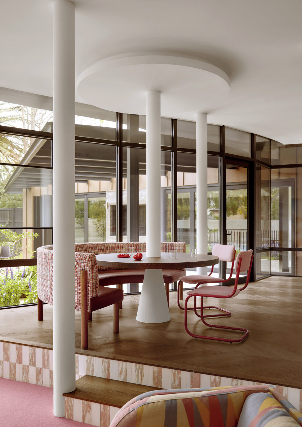 Light-filled breakfast nook featuring a built-in upholstered dining banquette, round pedestal table and colourful decorative details, creating a fresh and welcoming family dining space.