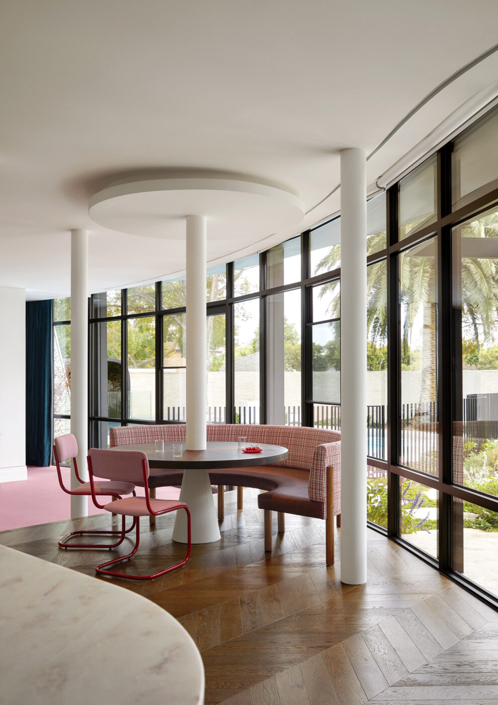 Light-filled breakfast nook featuring a built-in upholstered dining banquette, round pedestal table and colourful decorative details, creating a fresh and welcoming family dining space.