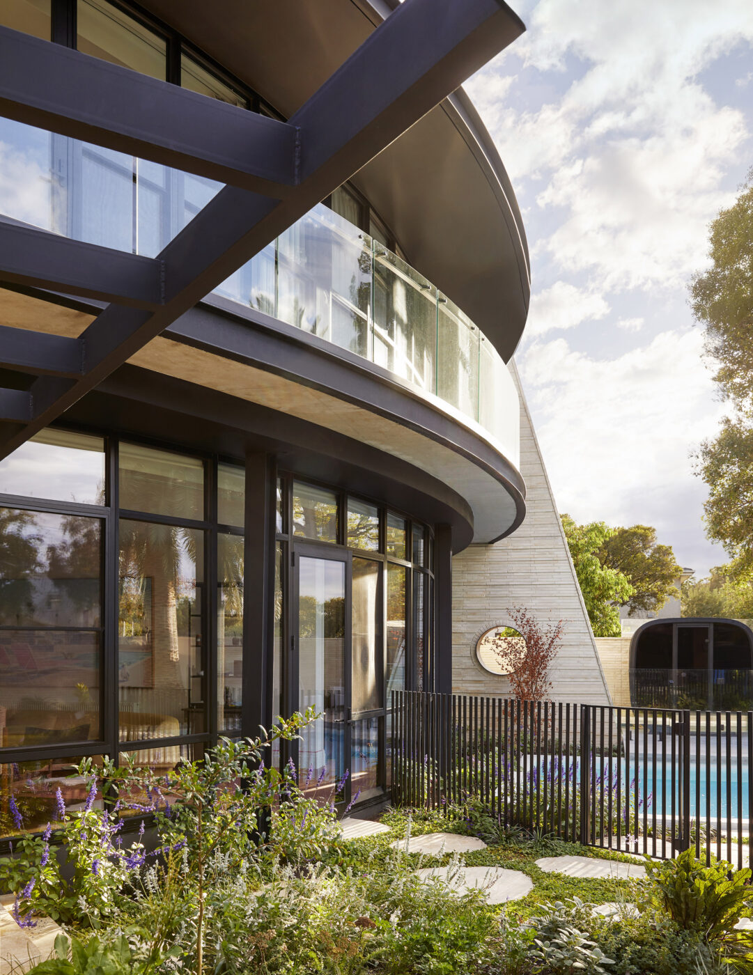 Garden view of a contemporary family home with bold architecture, expansive glazing and a flourishing kitchen garden, creating a seamless connection between indoor living and the landscape.