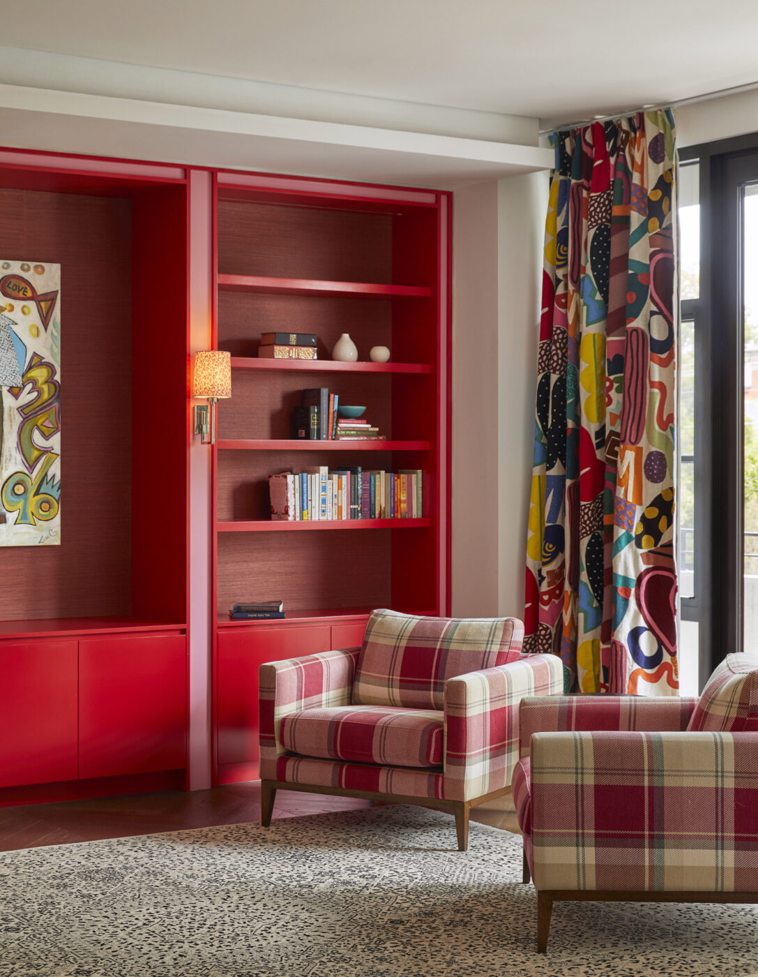 Contemporary parents' retreat with statement red cabinetry, pink accents, embroidered patterned drapery and red and white check lounge chairs, showcasing playful colour combinations and bespoke interior design.