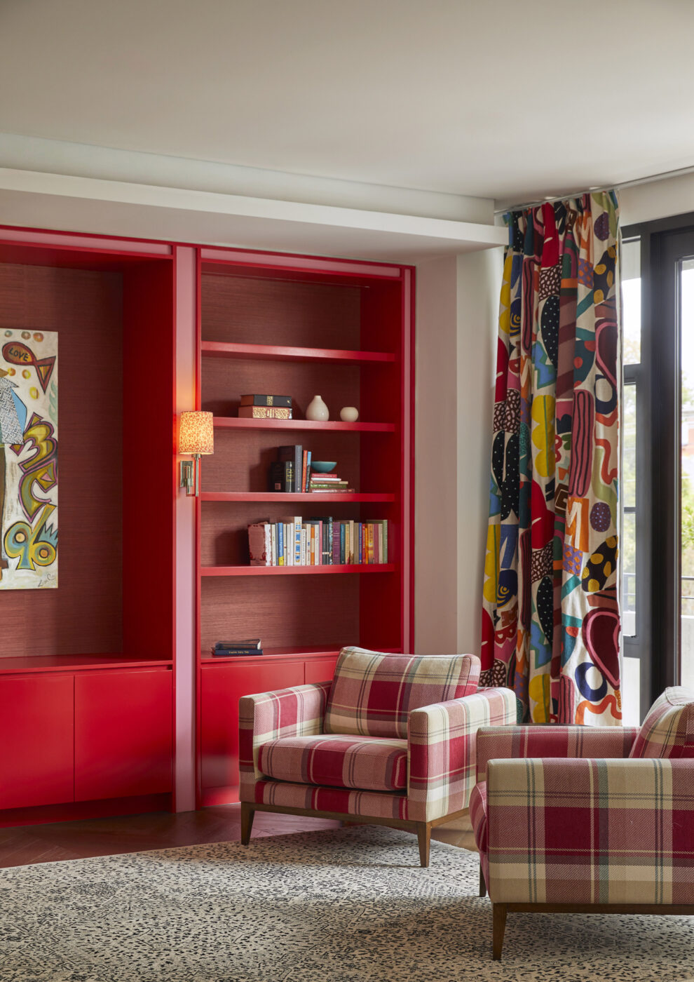 Contemporary parents' retreat with statement red cabinetry, pink accents, embroidered patterned drapery and red and white check lounge chairs, showcasing playful colour combinations and bespoke interior design.
