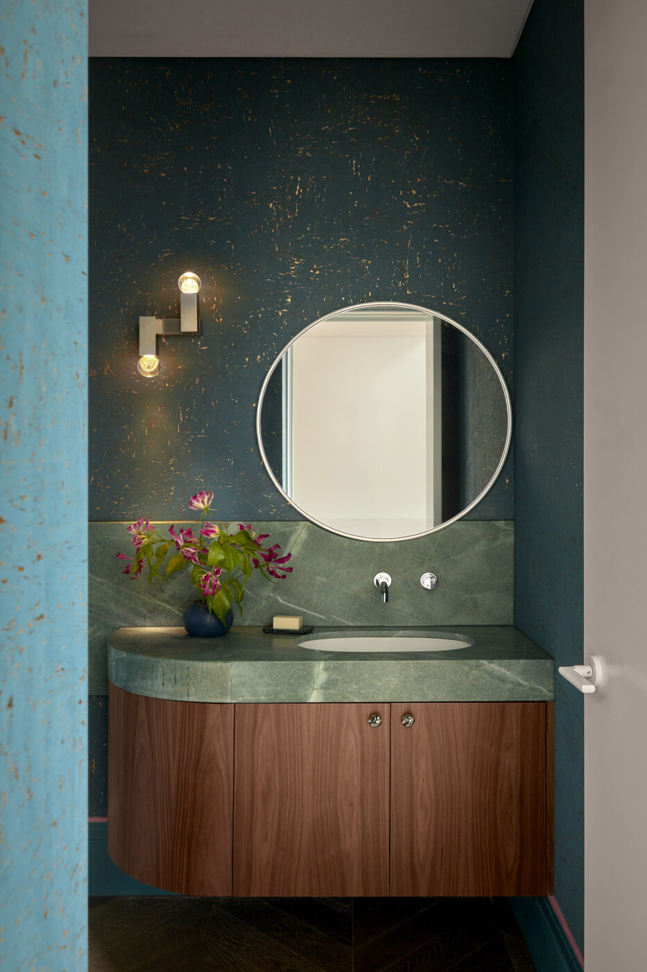 Contemporary powder room showcasing turquoise cork wallpaper, green stone detailing and decorative feature lighting, creating a dramatic yet welcoming atmosphere with rich natural textures.