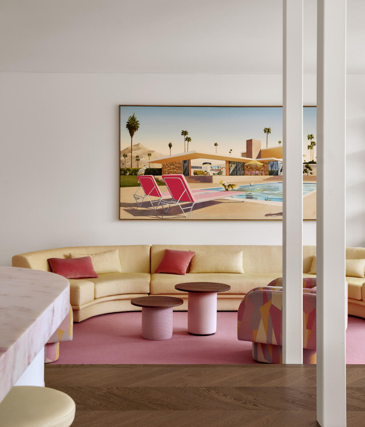 Elegant contemporary living room with a soft yellow modular sofa, blush pink goat hair rug, swivel chairs upholstered in graphic fabric and a large-scale artwork inspired by glamorous 1950s poolside photography.